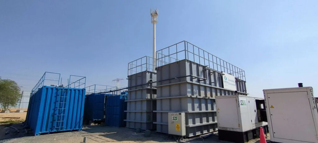Modular container building in an industrial site with safety railings and external staircase, likely used as temporary offices or worker accommodations.